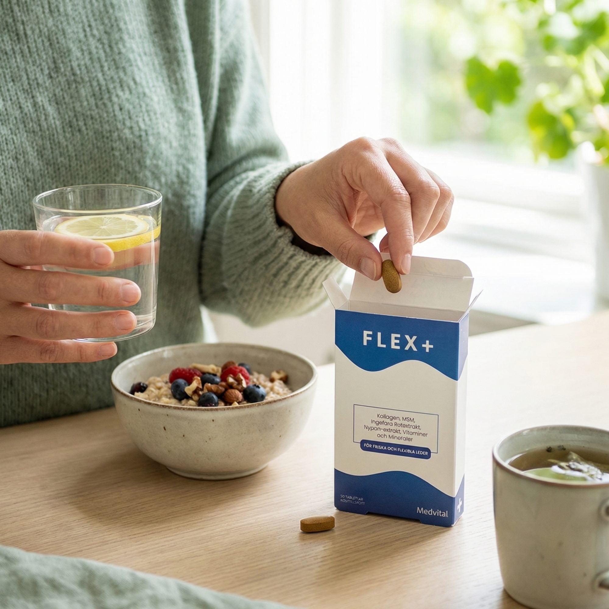 En hand tar en Flex+-tablett ur förpackningen vid frukostbordet, med ett glas vatten